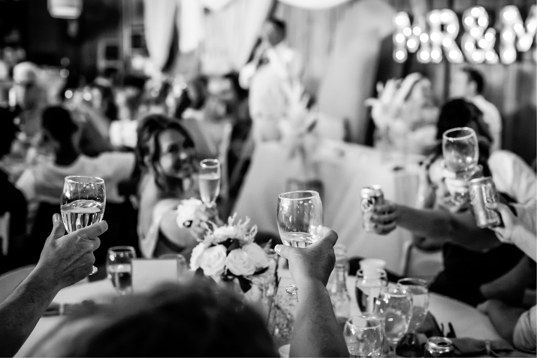 black and white photo of guests raising glasses during toasts