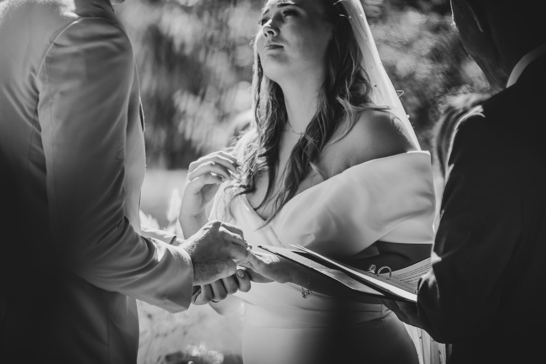 Black and white photo of bride gazing at groom during wedding ceremony