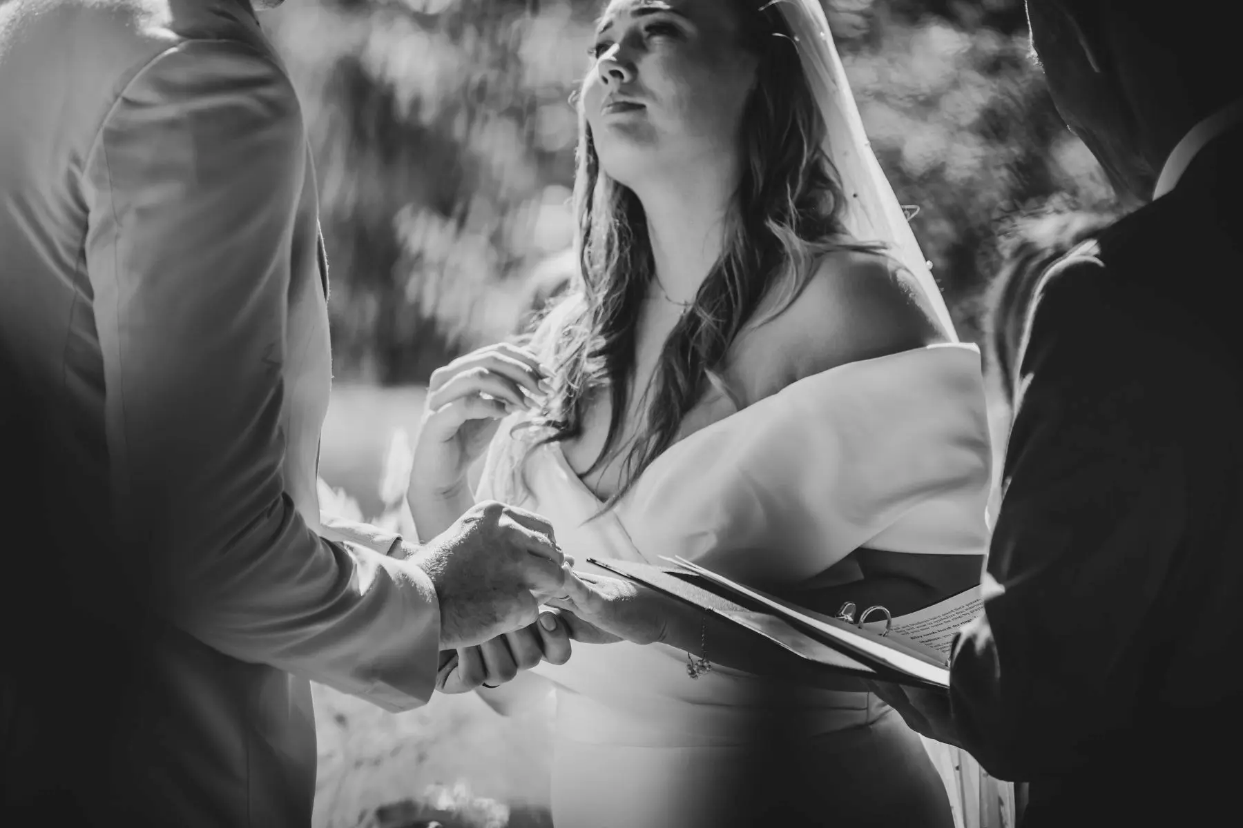 Black and white photo of bride gazing at groom during wedding ceremony