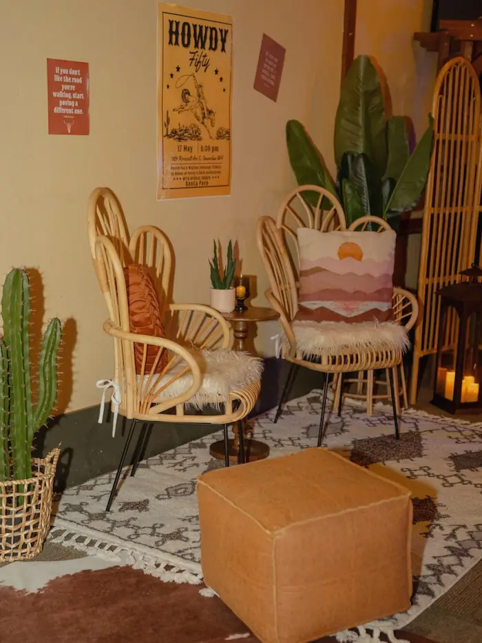 Nashville meets desert southwest, featuring rattan peacock chairs, a leather ottoman, cacti, and Howdy wall art
