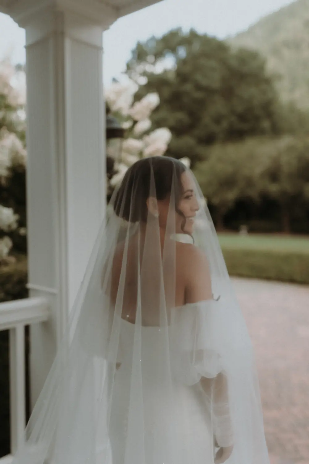 Portrait of a bride wearing a long sheer veil with mountain foliage in the background